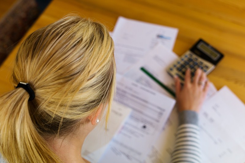 Blonde dame die iets aan het uitrekenen is op haar calculator